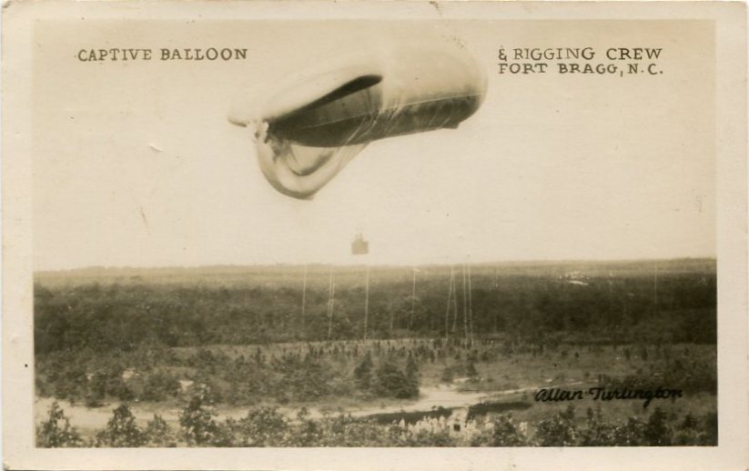 AIRReal-photo postcard of a photograph of a captive aerial balloon and rigging crew, with the balloon in flight over Fort Bragg, N.C., during the 1930s [circa 1930s