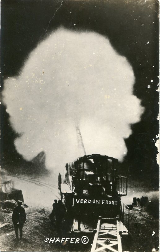 Real-photo postcard of a military railway artillery gun on train tracks near the Verdun front in France during World War I. The gun is pictured firing at night (Undated) [Photograph by: Shaffer].