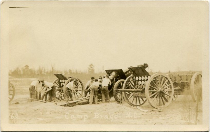 Real-photo postcard of a photograph of an unidentified field artillery crew practicing loading shells and firing a gun on the firing range at Camp Bragg, N.C., taken be