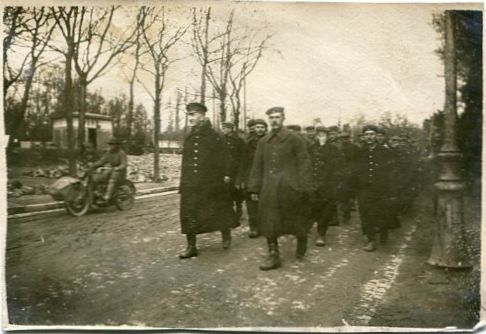 Snapshot of a column of German prisoners of war being marched down a street in an unidentified French town by U.S. Army soldiers during World War I. An Army soldiers on