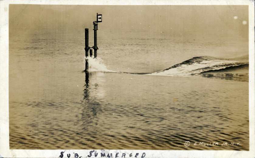 Real-photo postcard of a photograph of a U.S. Navy submarine submerging below the water somewhere along the Atlantic Coast during World War I.